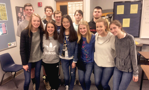 A group of high school students posed together in a classroom.