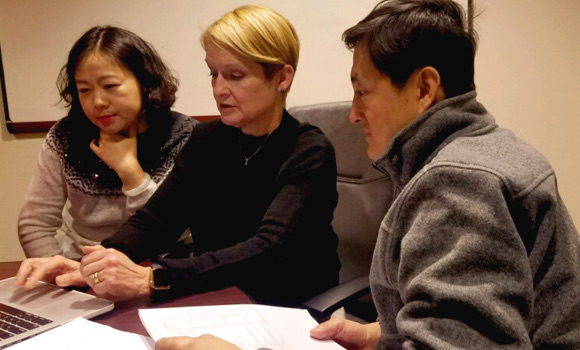 Three adults seated at a table reviewing paperwork together during a school meeting.