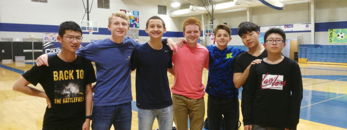 A group of high school students standing shoulder to shoulder in a school gymnasium.
