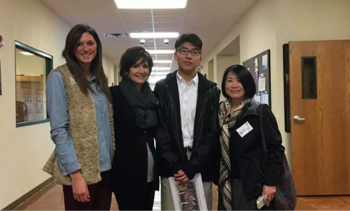 Four people standing together in a school hallway.