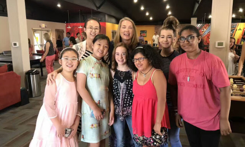 A group of students and adults standing together indoors, smiling for the camera.