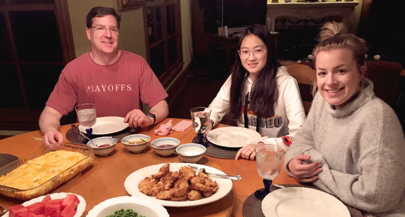 Three people sharing a home-cooked meal around a dining table.